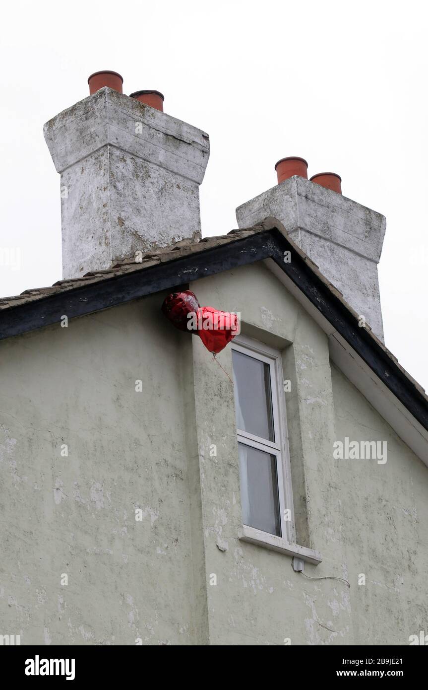 2 Liebe Herz valentine Helium Ballons, die vor einem geschlossenen Fenster in London schweben. Stockfoto