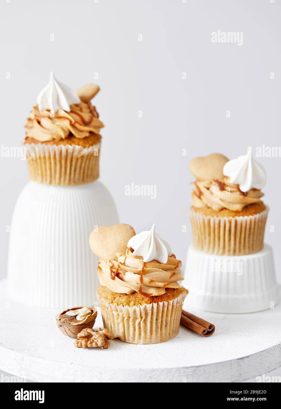 Karottenkuchen mit Karamell, Walnüssen und Gewürzen, dekoriert mit herzförmigem Keks, Meringue und salzigem Karamell auf weißem Hintergrund. Freier Speicherplatz für y Stockfoto