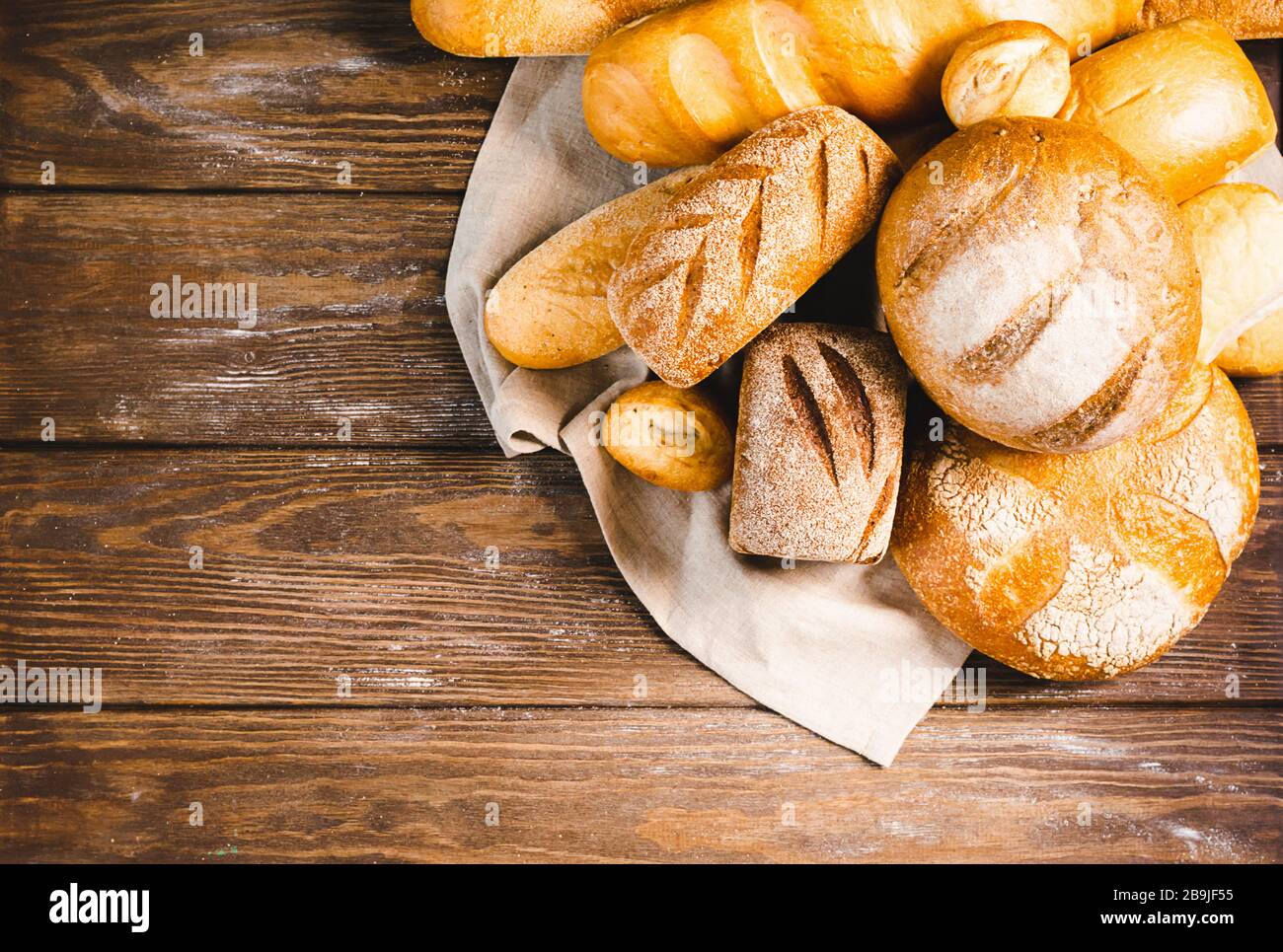 Frisch gebackenes Brot mit einer goldenen Kruste, Brot, Brötchen, weiß, Roggen auf einem rustikalen Holzhintergrund mit sil rustikal. Flaches Layout Stockfoto