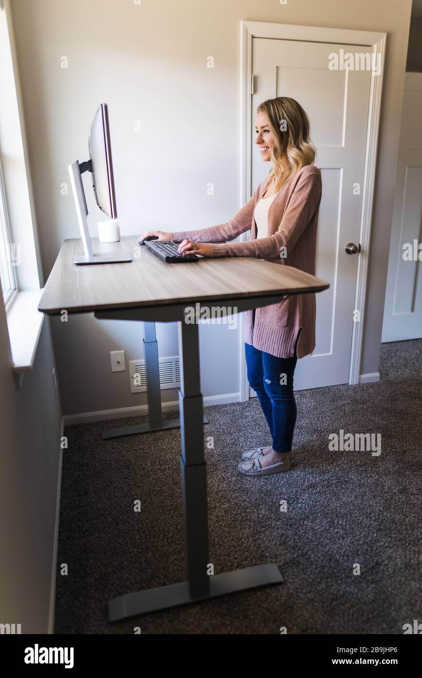 Junge Frau, die an ihrem Schreibtisch in ihrem Heimbüro an ihrem Computer arbeitet Stockfoto