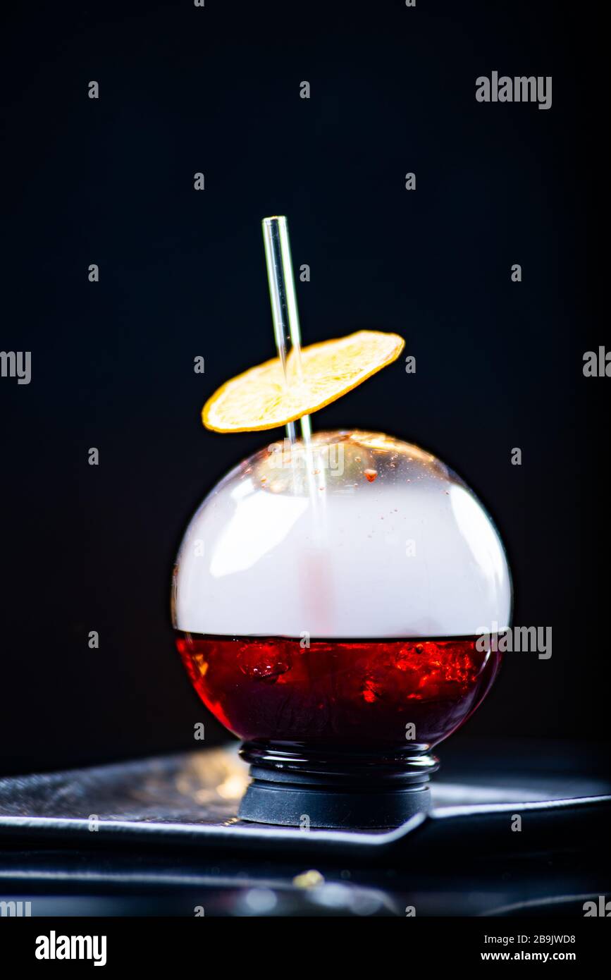 Kugelglas mit Rauch und Alkohol. Karamellisierte Zitronenscheiben. Rauch auf schwarzem Hintergrund. Stockfoto