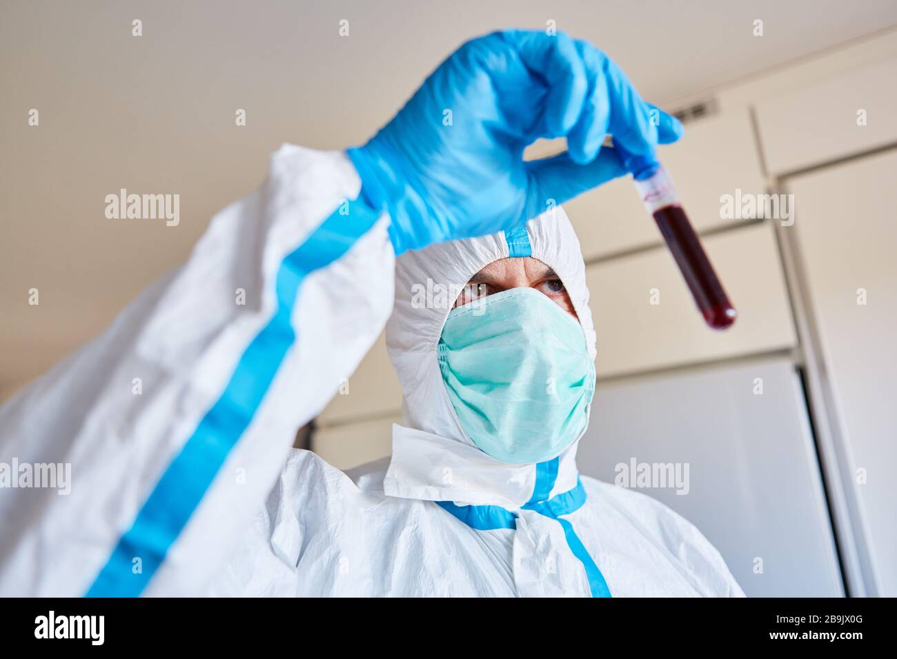 Laborangestellter in Schutzkleidung mit Covid-19-Blutprobe zur Prüfung im Labor Stockfoto