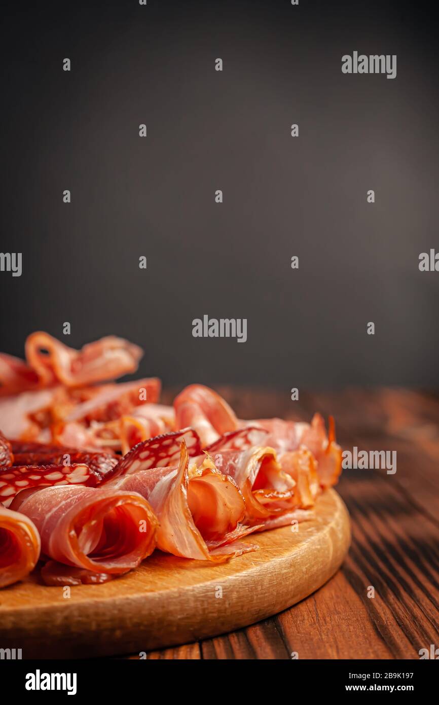 Verschiedene Fleisch-Snacks auf einem Holzschnittbrett. Wurst, Schinken, Speck, geräuchertes Fleisch. Stockfoto von Fleischprodukten mit Leerplatz. Stockfoto