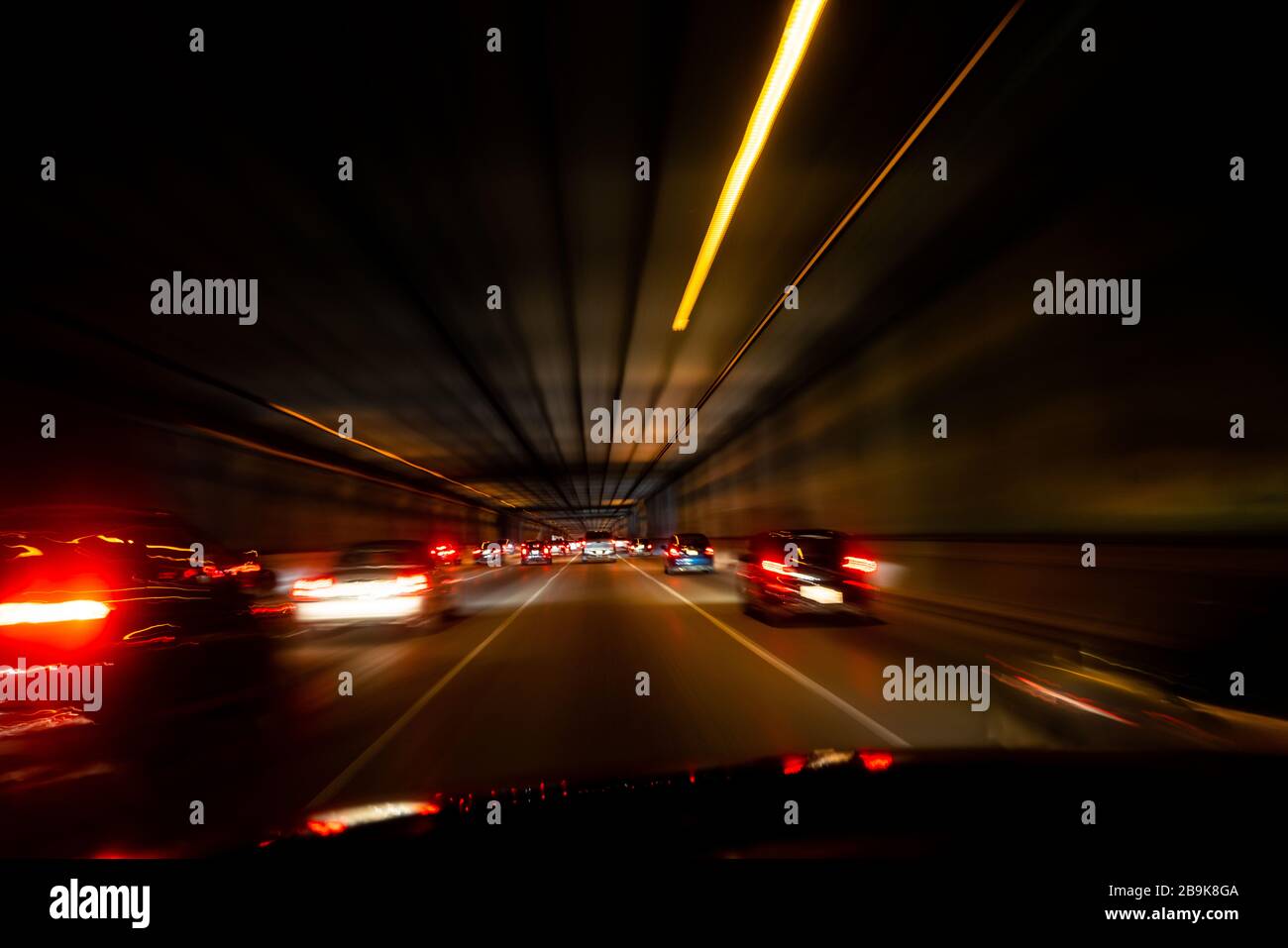 POV der Heckleuchten im Auto verschwimmen während der Fahrt durch den Tunnel Stockfoto