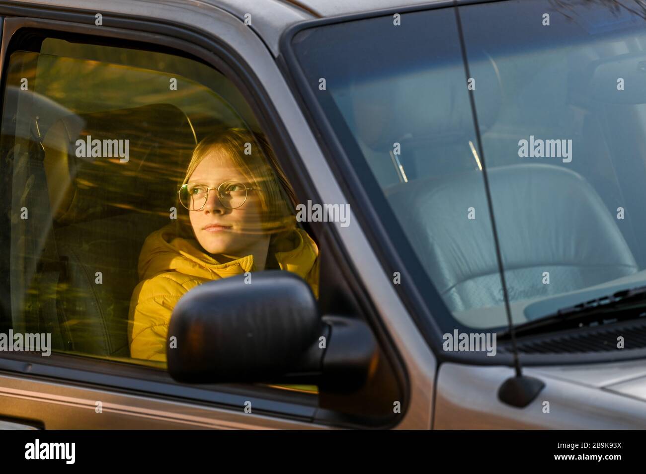 Junge im Auto sitzen Blick aus Passanger Fenster tword Sonnenuntergang Stockfoto