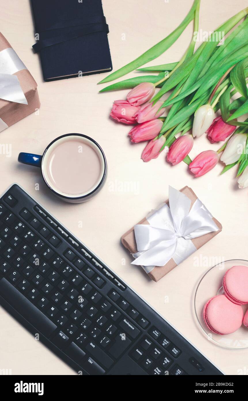 Kaffeetasse, Tulpenblumen im Frühling und rosafarbene Makronen auf Pastelltisch Draufsicht. Begrüßung für Womans oder Mothers Day. Flaches Lay. Stockfoto