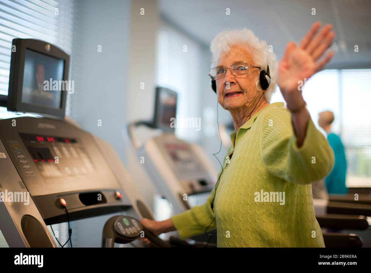 Ältere Frau mit Kopfhörern auf Laufband. Stockfoto