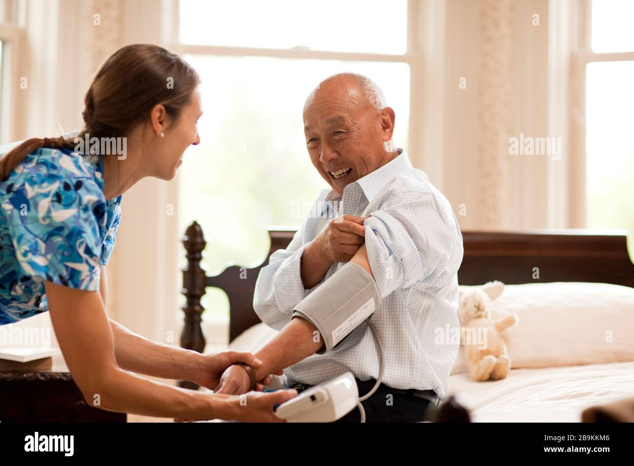 Älterer Mann seinen Blutdruck durch eine Krankenschwester zu Hause geprüft zu haben. Stockfoto