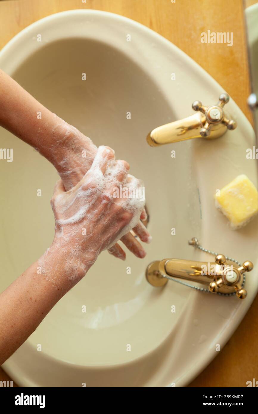 Frau wäscht ihre Hände mit Seife an einem Waschbecken von oben Stockfoto