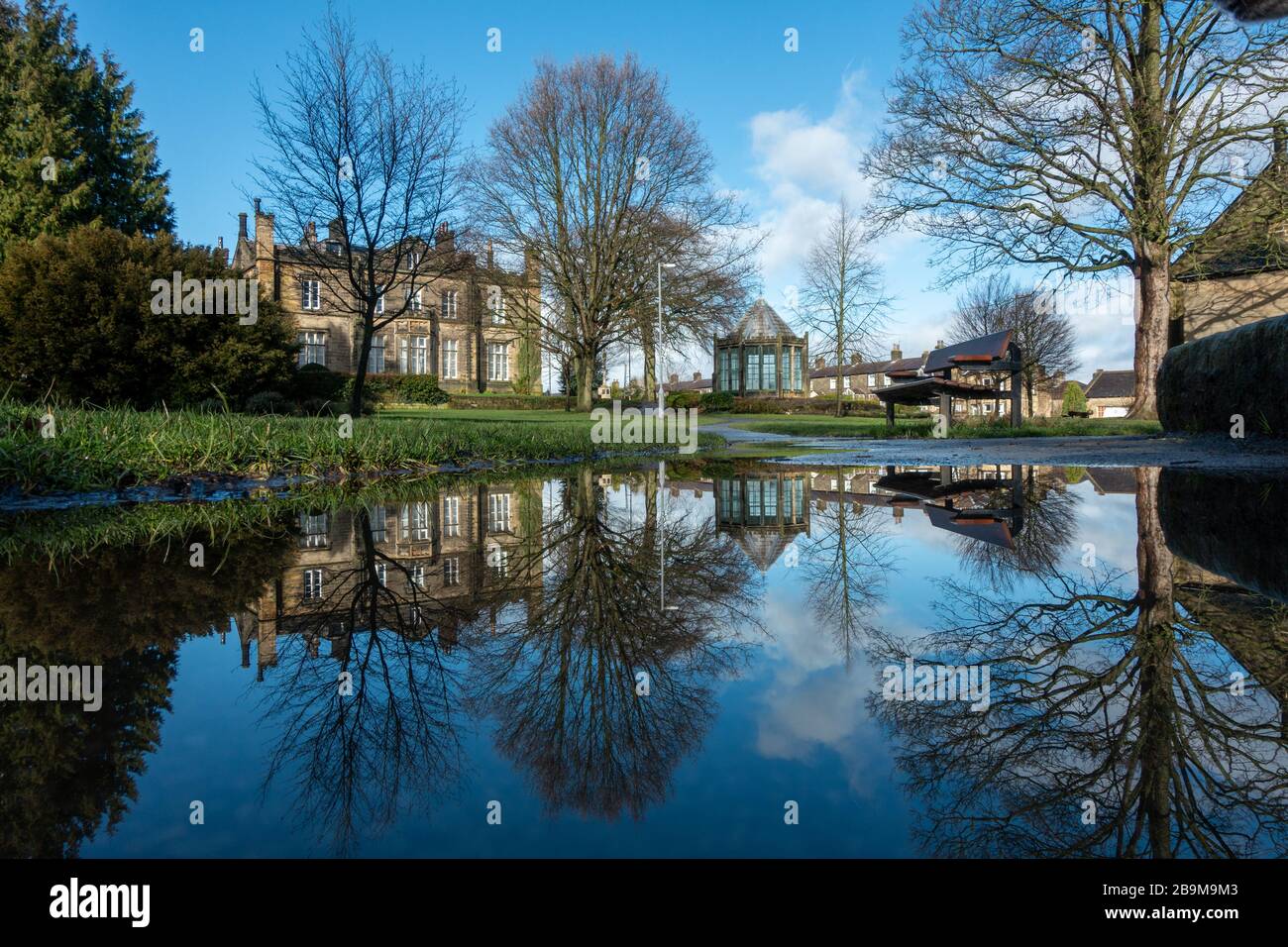 Reflexionen in einer Pfütze des malerischen Yorkshire Dorfes Burley-in-Wharfedale, West Yorkshire, England Stockfoto