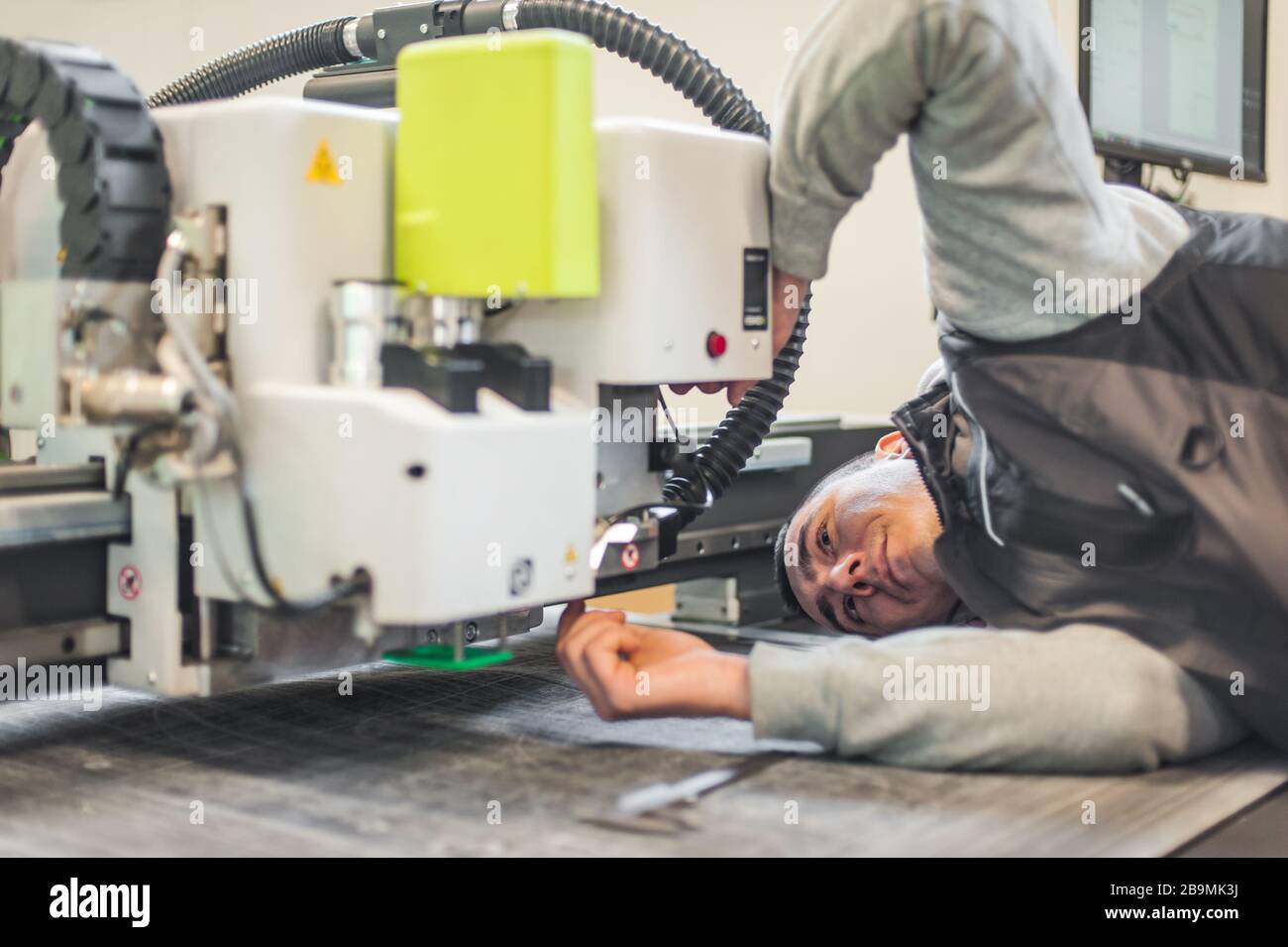 Elektroingenieur repariert einen Messerschneidkopf an großen CNC-Maschinen für die numerische Steuerung von Druck- und Schneidmaschinen Stockfoto