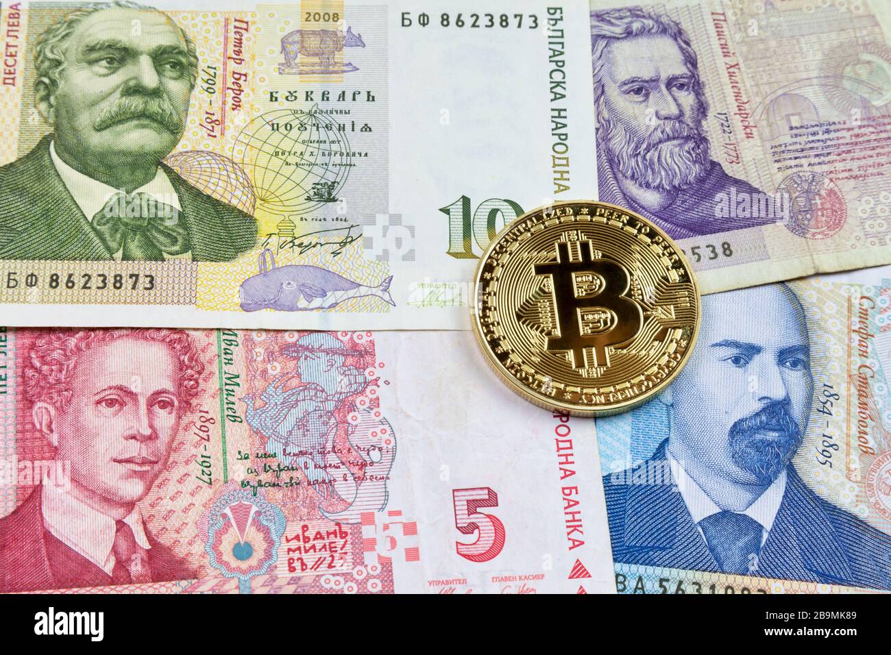Nahaufnahme einer goldenen Bitcoin-Münze auf einem Stapel bulgarischer Lev-Banknoten. Stockfoto