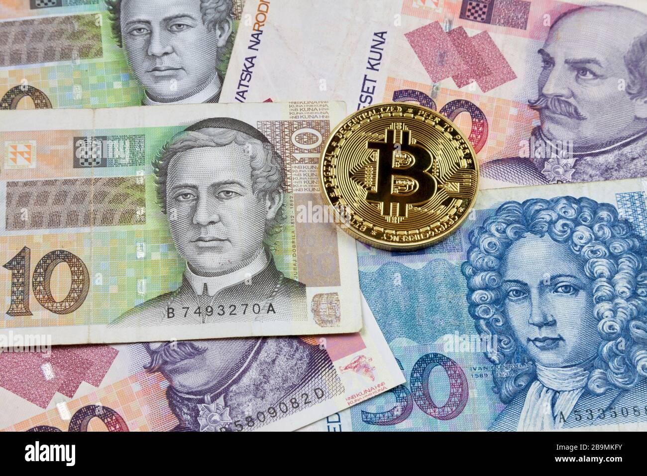Nahaufnahme einer goldenen Bitcoin-Münze auf einem Stapel kroatischer Kuna-Banknoten. Stockfoto