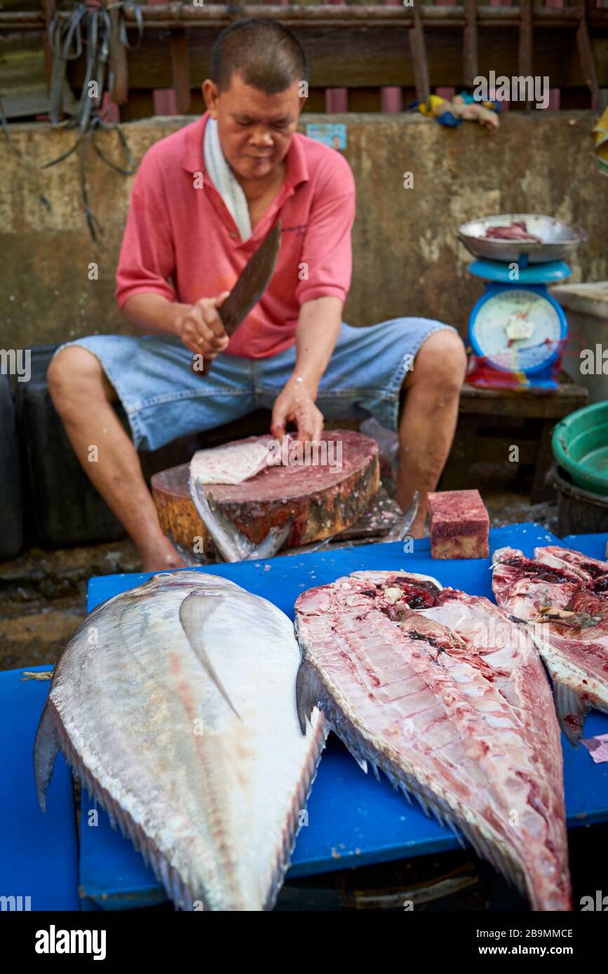 Fischhändler schneiden Fisch in einem Stand des öffentlichen Marktes für Kohlenstoff. Stockfoto