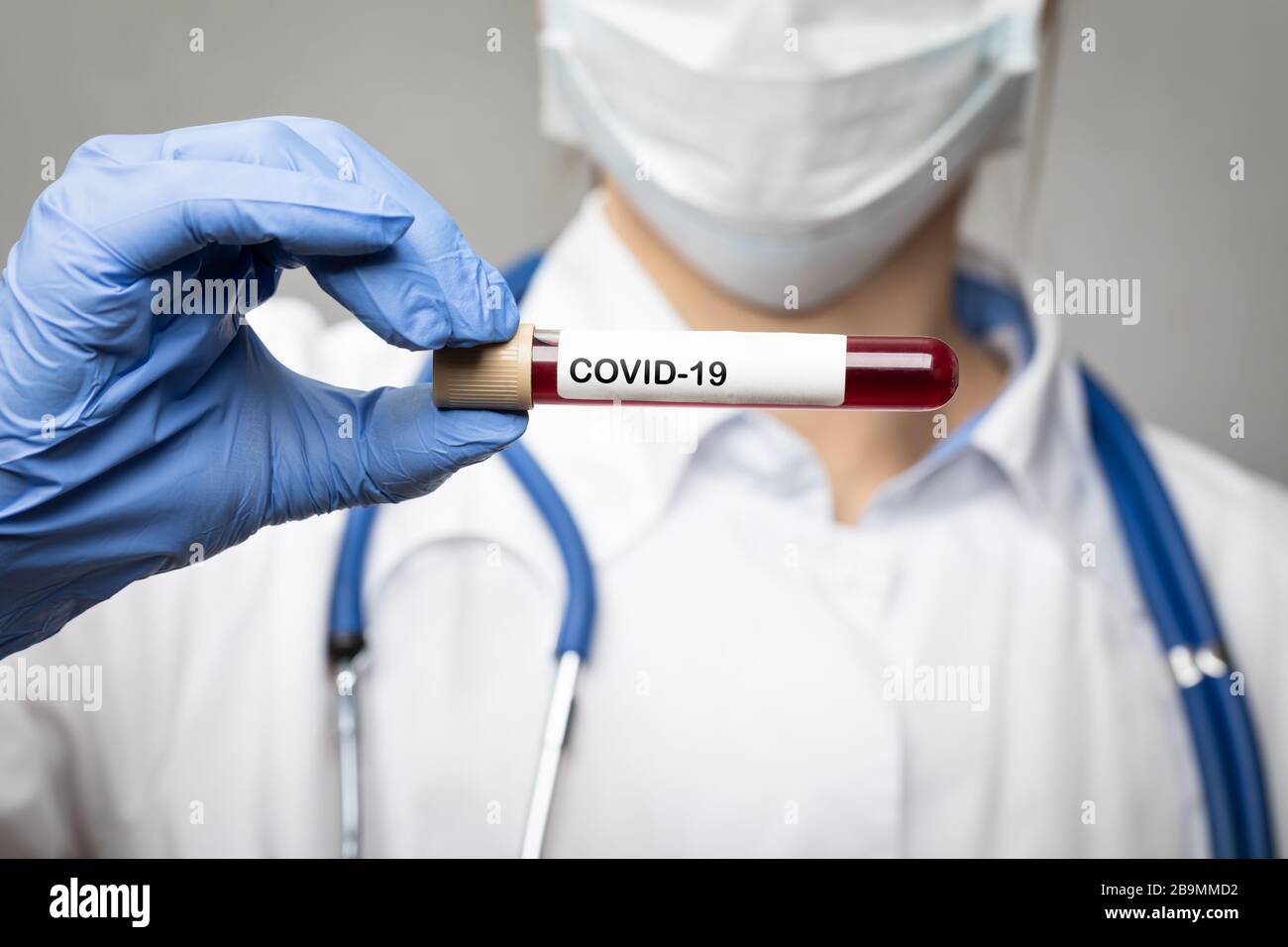 Nahaufnahme des Arztes mit chirurgischer Schutzmaske und Handschuhen zur Aufnahme des Coronavirus Disease 2019 (COVID-19)-Tests oder des Impfstoffröhrchens - Epidemievirus Stockfoto