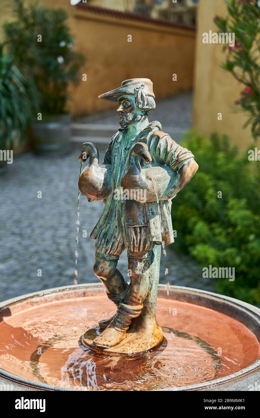Eine Bronzestatue und ein Springbrunnen eines Mannes, der zwei Enten (oder Gänse) hält. In einem Garten eines Schlosses Hohenschwangau stehend. Stockfoto