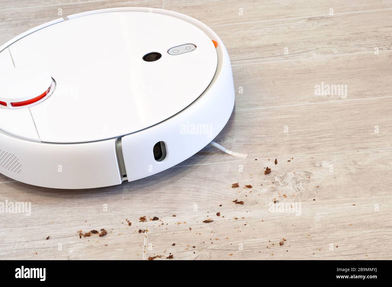 Der Roboter-Staubsauger entfernt Brotkrümel aus dem Laminatboden. Intelligente Reinigungstechnologie. Stockfoto