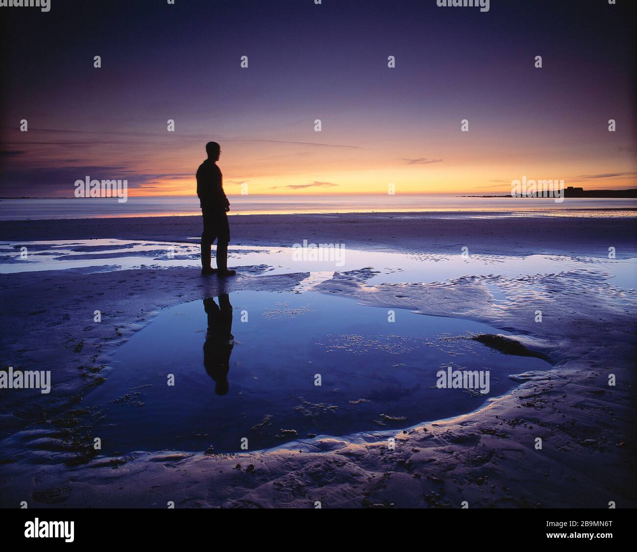 Kanalinseln. Guernsey. Silhouette des jungen Mannes, der in der Dämmerung am Strand von Vazon steht. Stockfoto