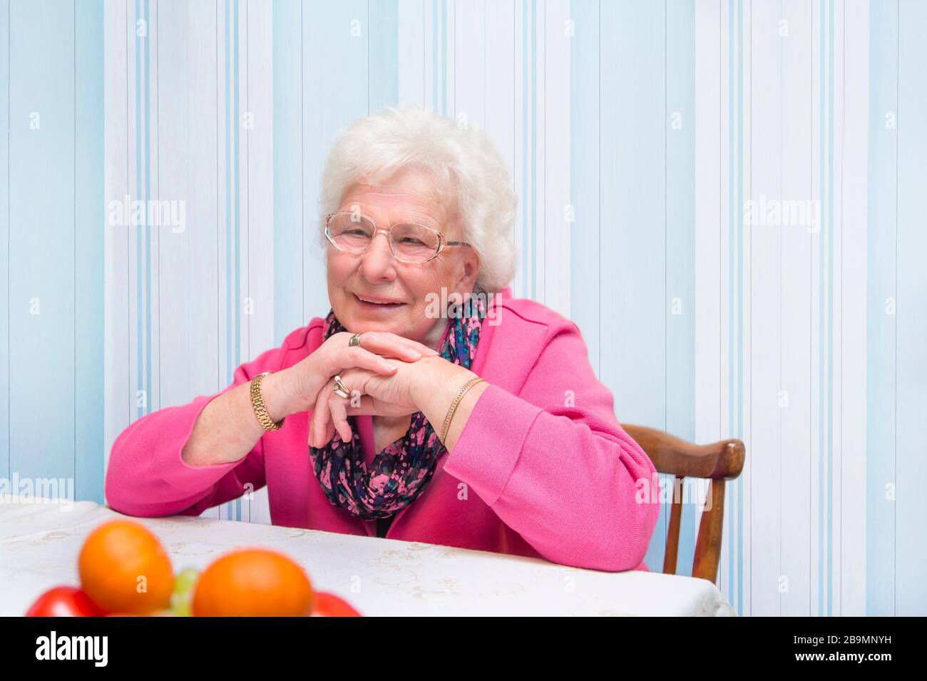 80 Jahre alte Frau, die allein in der Wohnung sitzt. Sie gehört der Risikogruppe für Covid 19 an. Inländische Quarantäne-Töne. Sie freut sich über den Kontakt Stockfoto