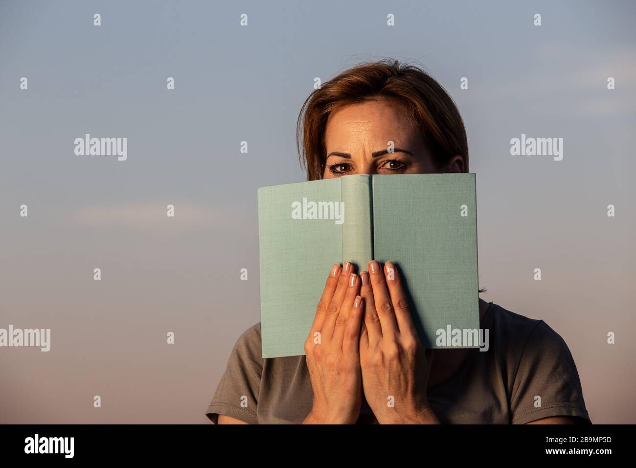 Junge Frau hinter einem Buch Stockfoto