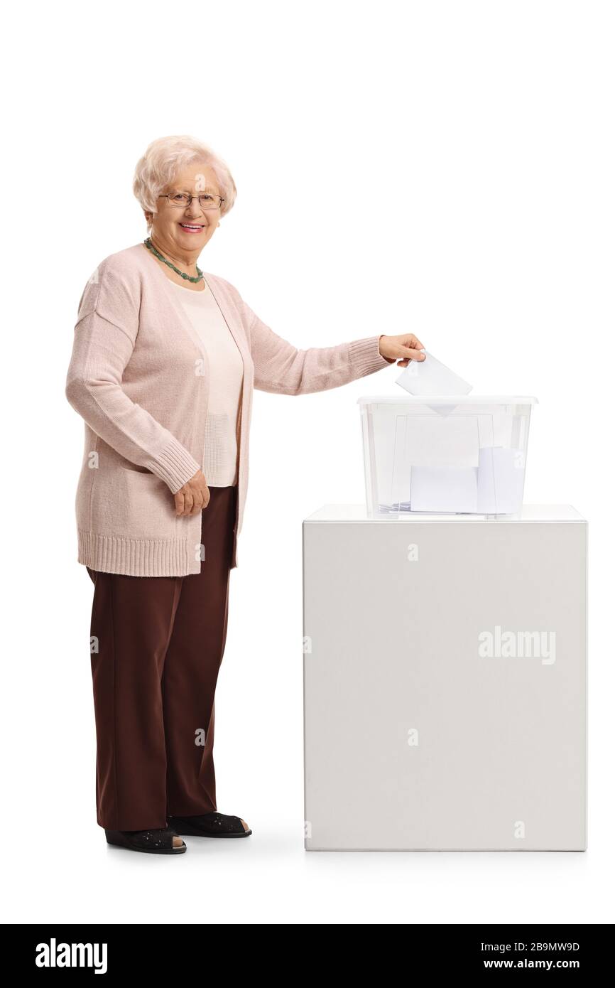 Eine ältere Frau, die in einer Wahlurne eine Stimme abgegeben hat und die Kamera auf weißem Hintergrund sieht, wurde in voller Länge aufgenommen Stockfoto