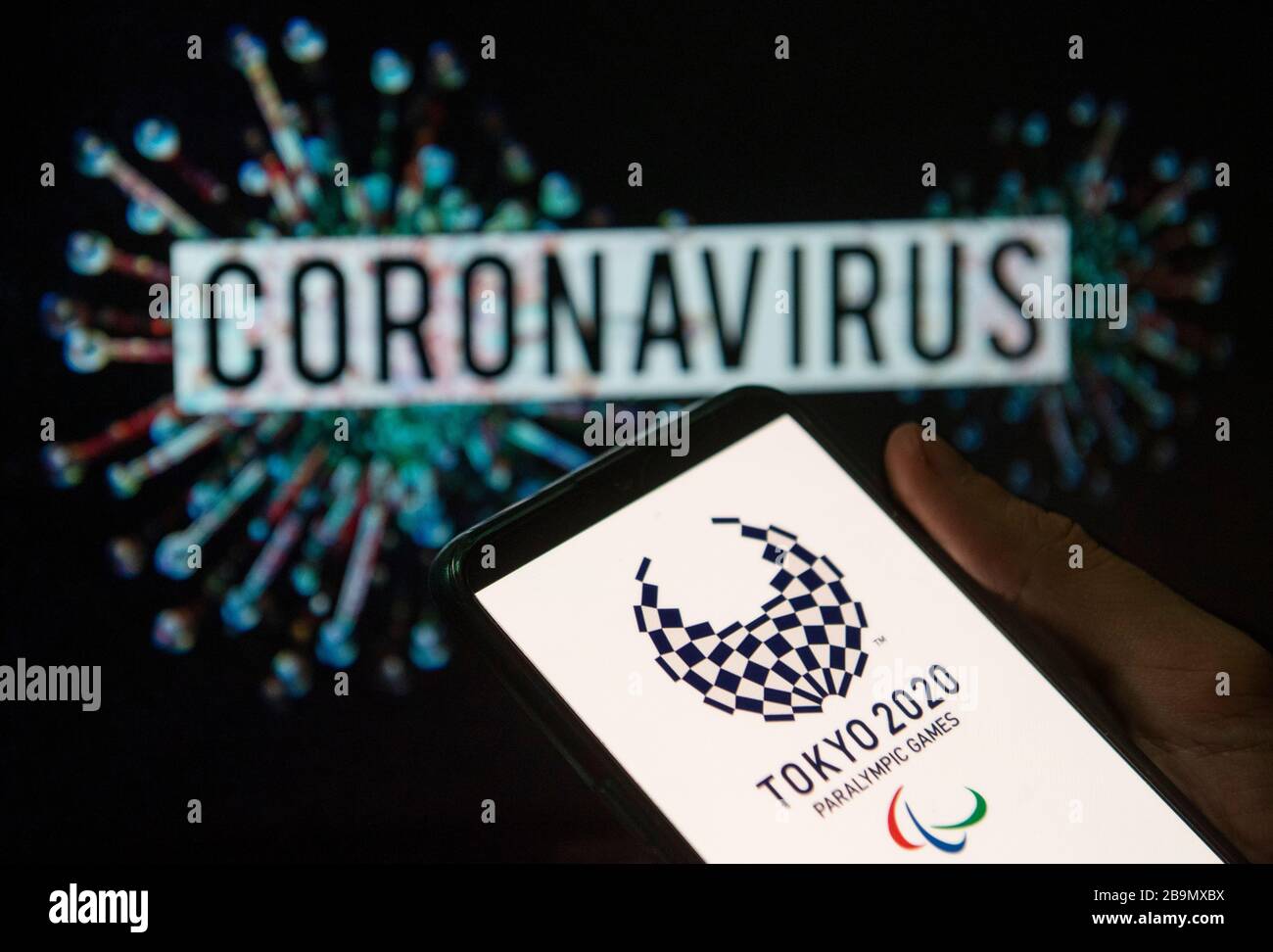 In dieser Abbildung wird das Logo der Paralympics 2020 in Tokio auf einem Smartphone mit einem Computermodell des Coronavirus COVID-19 im Hintergrund angezeigt. Stockfoto
