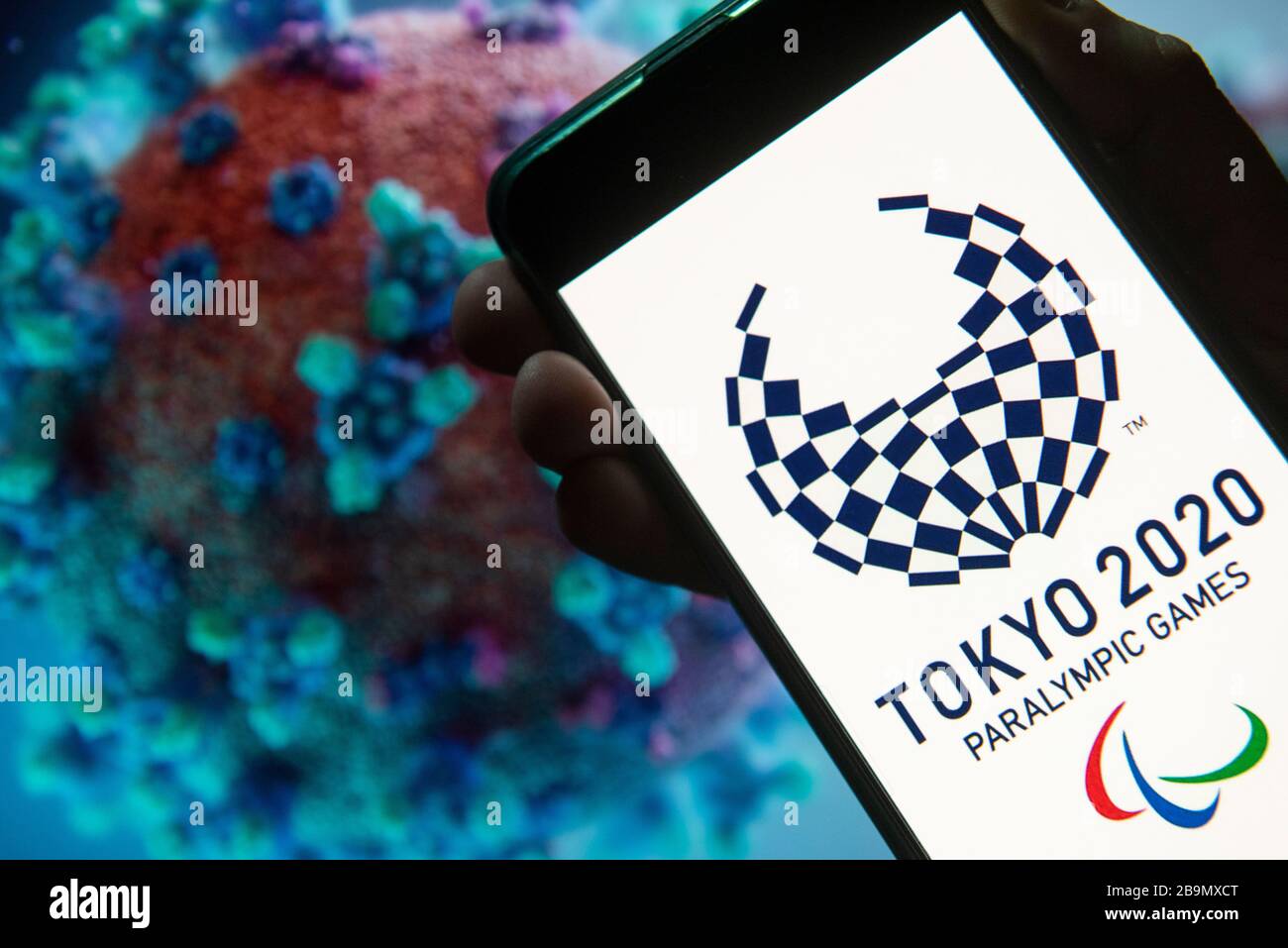 In dieser Abbildung wird das Logo der Paralympics 2020 in Tokio auf einem Smartphone mit einem Computermodell des Coronavirus COVID-19 im Hintergrund angezeigt. Stockfoto