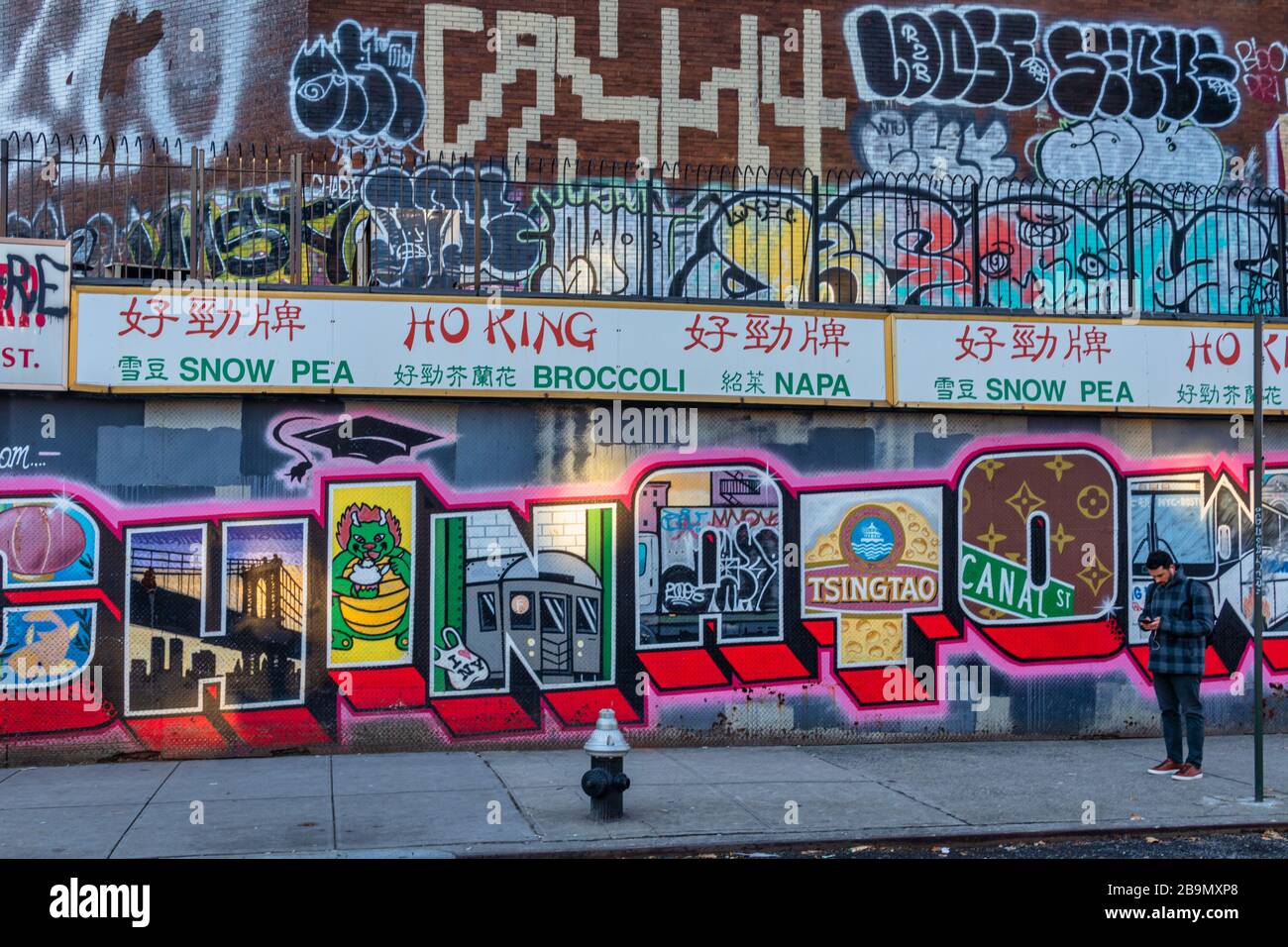 Chinatown Nachbarschaft in Lower Manhattan NYC Tageslichtansicht zeigt Geschäfte in der Straße mit chinesischen Buchstaben, Graffiti-Kunst und Menschen zu Fuß Stockfoto