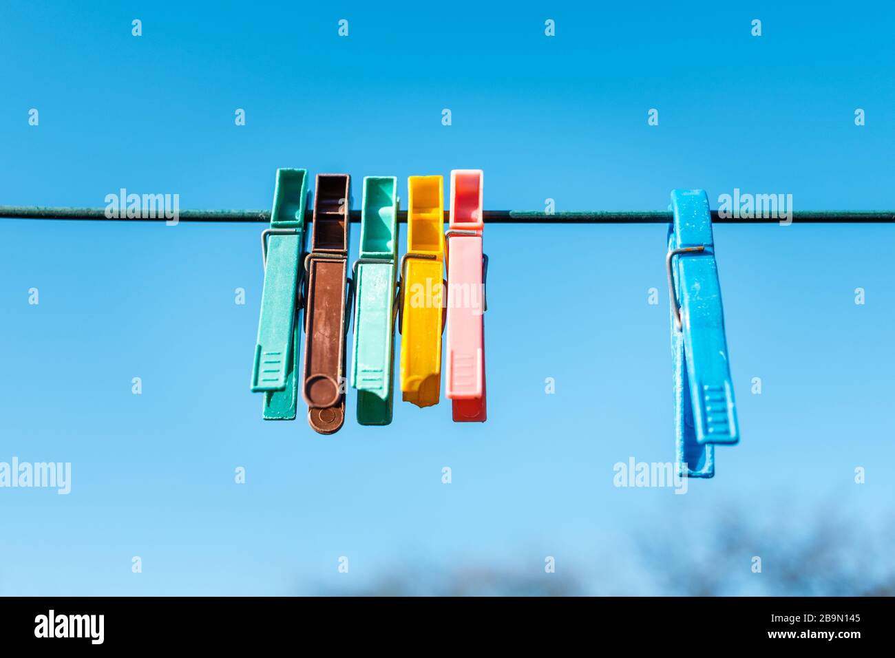 Sechs Wäscheklappen, die an einer Linie gegen einen reichen blauen Himmel hängen Stockfoto