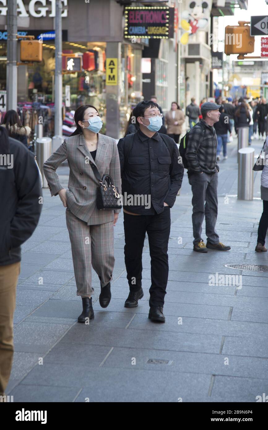 Das Paar läuft während der Ausbreitung des Coronavirus kurz vor der von New York vorgeschriebenen Abschaltung auf der 7th Avenue am Times Square hoch. Stockfoto