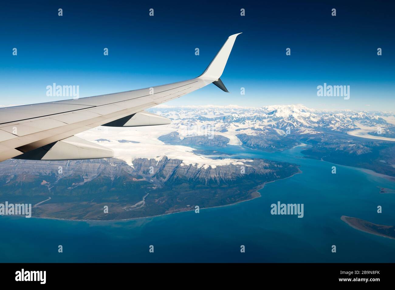 Blick auf den Flugzeugflügel mit schneebedeckten Bergen in einer kalten Umgebung. An Bord eines Milk Run Flugs, zwischen zwei kleinen Städten im US-Bundesstaat Alaska. Stockfoto