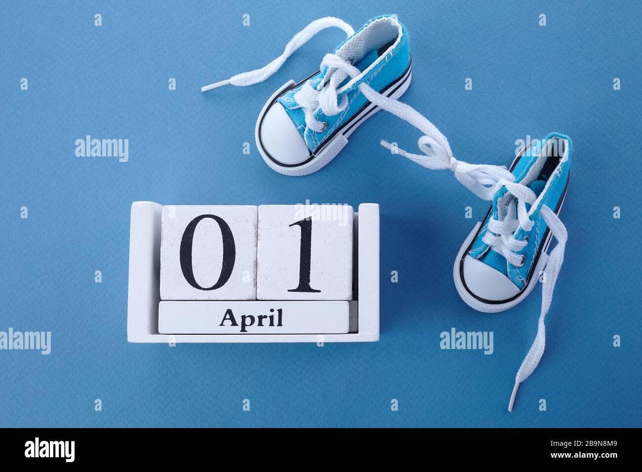 April Narrentag. Überraschungssymbol. Schnürsenkel auf blauem Holzhintergrund zusammengebunden. April Narr. Stockfoto
