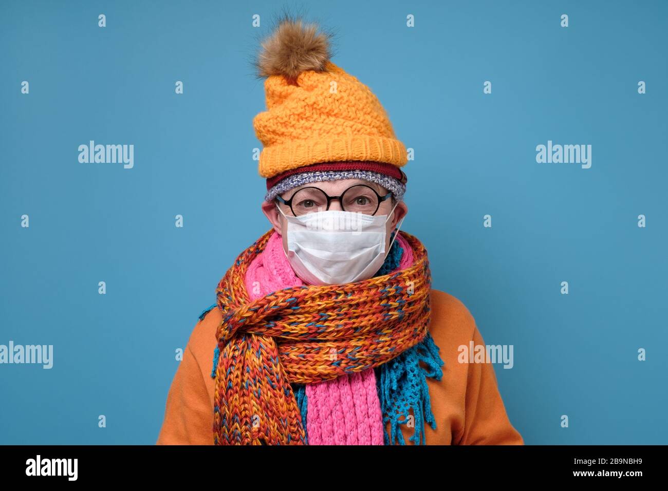 Reifer Mann mit medizinischer Maske als Schutz vor Covid-19 und witziger Hutbrille und Schal. Stockfoto