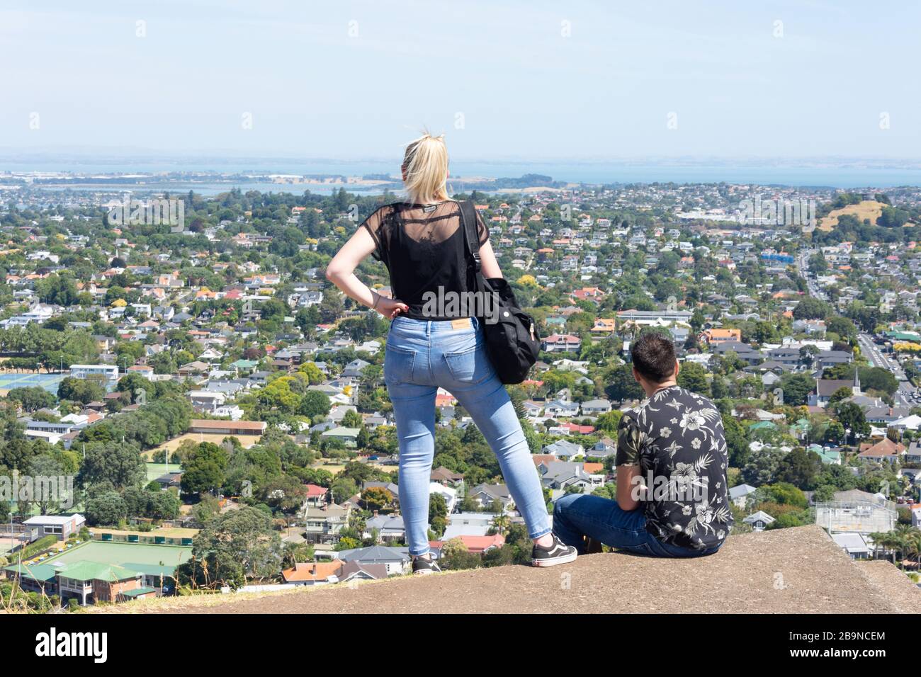Ein Paar, das vom Gipfel des Mount Eden (Maungawhau), Mount Eden, Auckland, Neuseeland, einen Blick auf die Vorstadt von Epsom hat Stockfoto