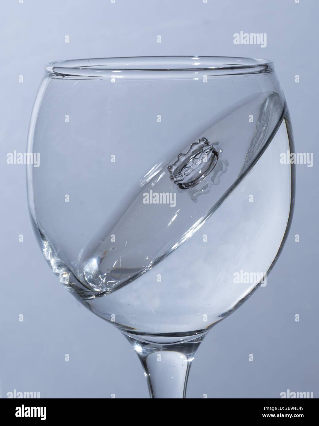 Ein Glas Wasser, ein Tropfen gefallen, isoliert auf weißem Hintergrund Stockfoto