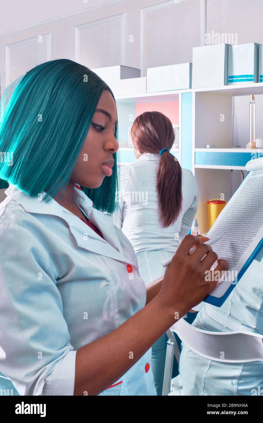 Coronavirus Testlabor, weiblicher afrikanischer Arzt, Krankenschwester oder Medizinstudent in weißem Mantel liest Notizen auf Notizblock. Junge professionelle Schecks werden immer wieder aufgenommen Stockfoto