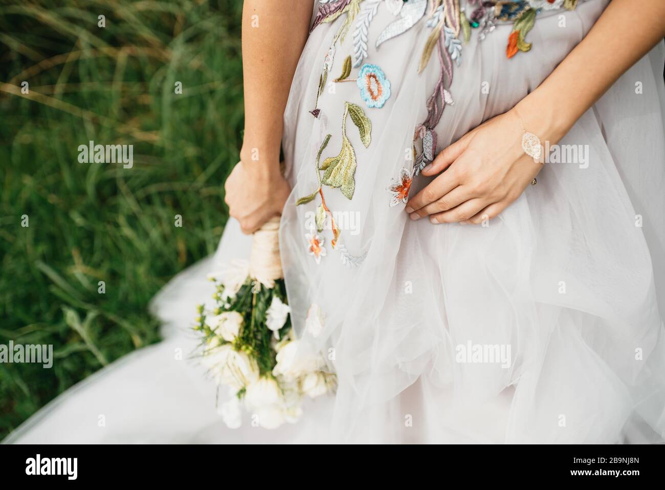 Die Frau in einem schönen Hochzeitskleid mit einem Blumenstrauß in der Hand Stockfoto