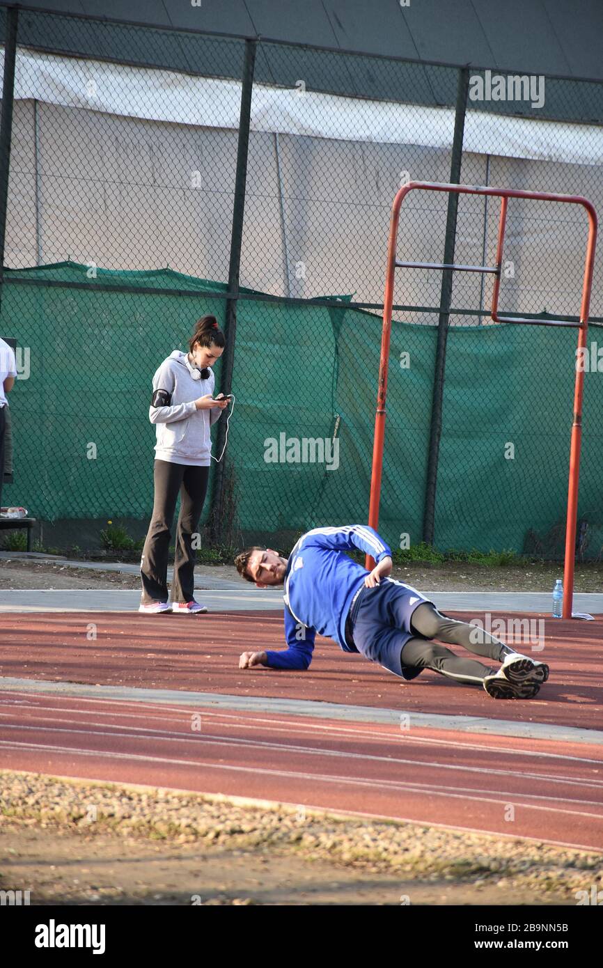 Sportzentrum für Erholung in Belgrad. Ein junger Mann macht körperliche Übungen und ein Mädchen steht und schaut auf das Telefon Stockfoto