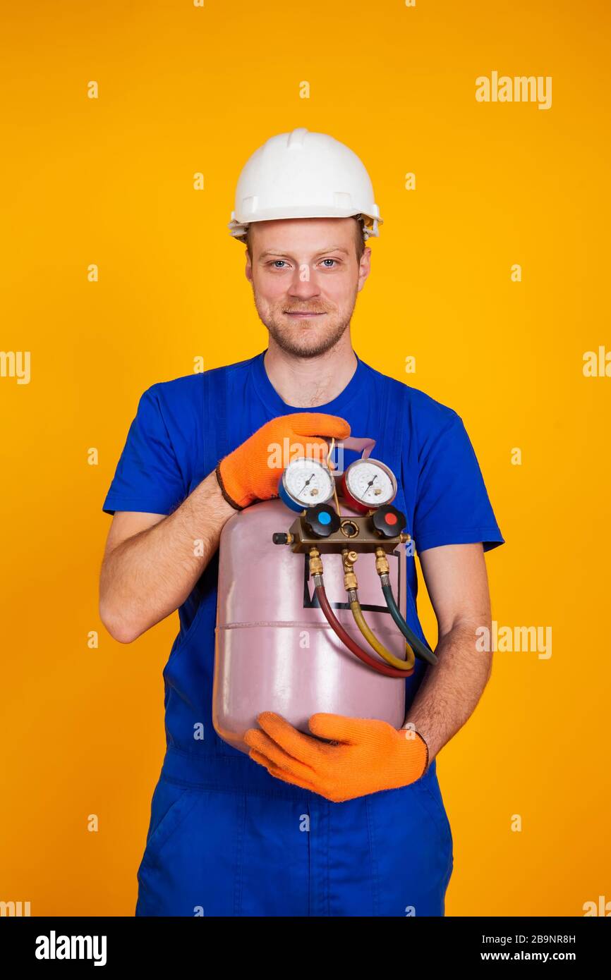 Ein Reparaturmann der männlichen Klimaanlage hält einen Freilaufzylinder in den Händen, um die Klimaanlage zu lüften. Betankungsfreianlagen. Stockfoto