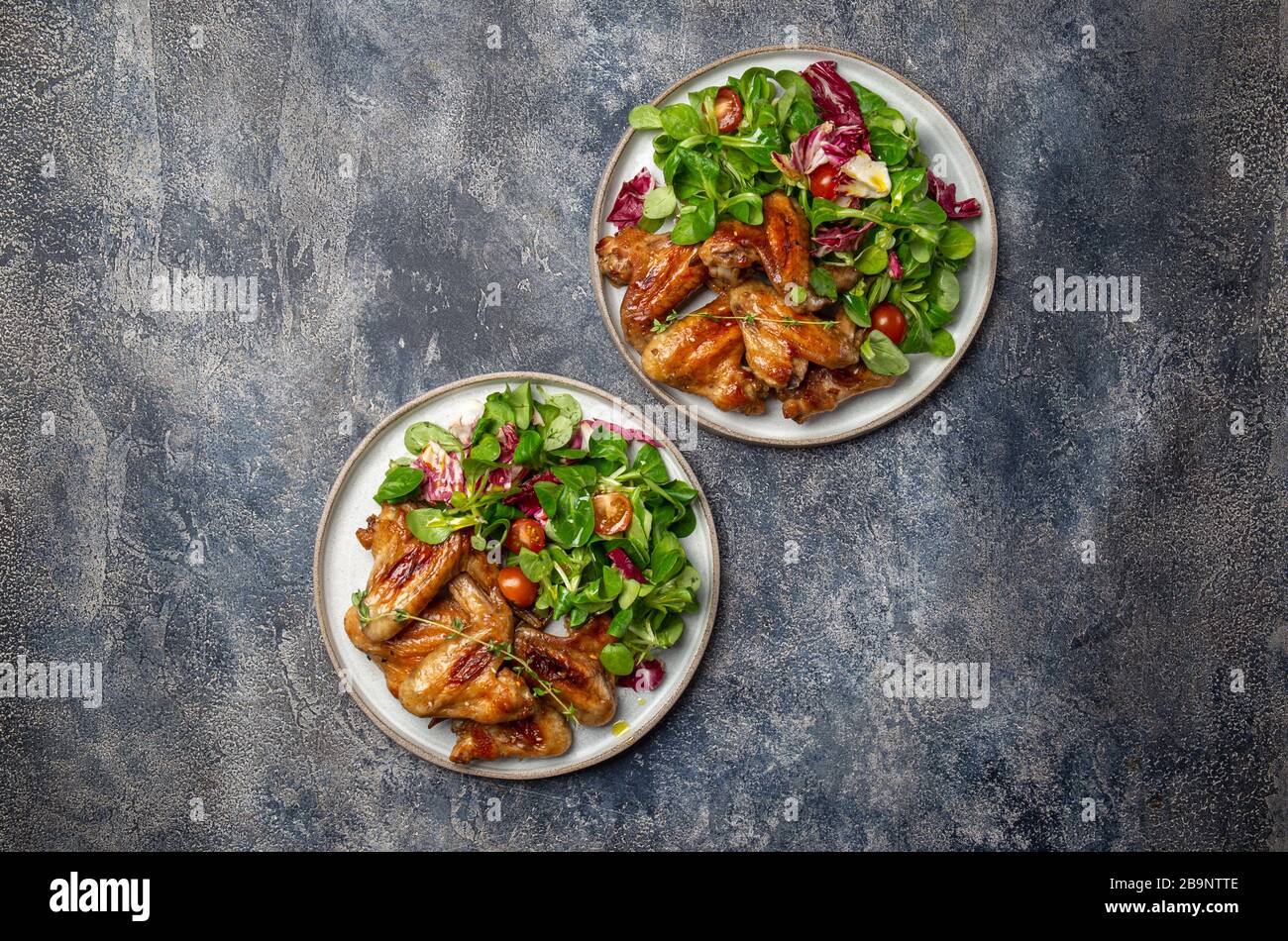 Geröstete bbq-Flügel mit grünem Salat mit Tomaten. Draufsicht Stockfoto
