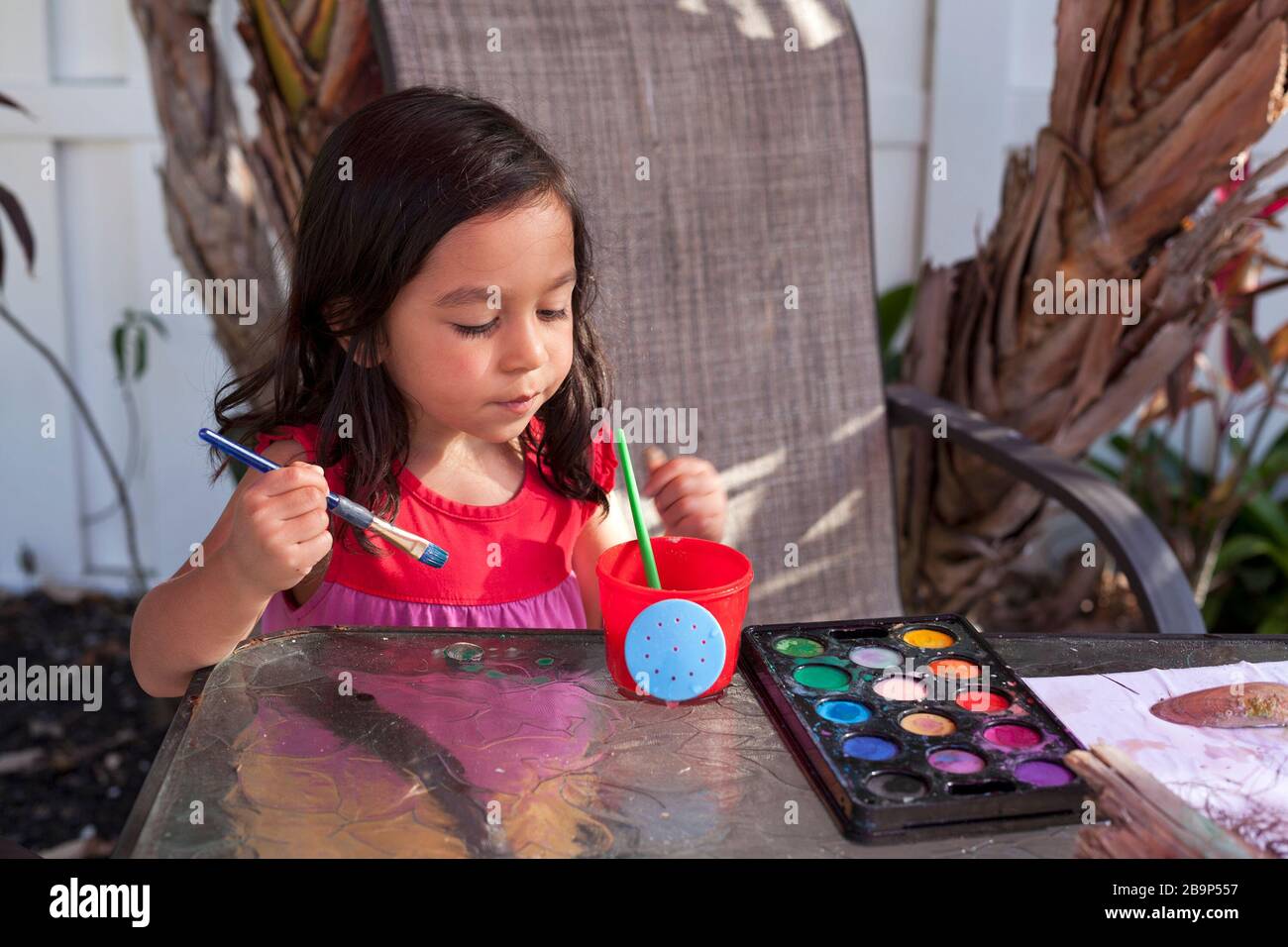 Ein vierjähriges Mädchen malt im Freien ein Seeschell. Stockfoto