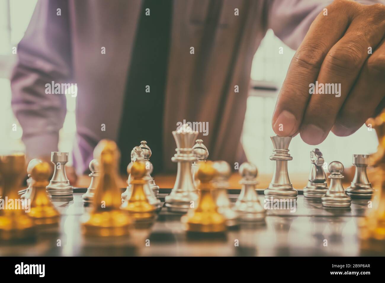 Schachspiel auf Schachbrett hinter dem Hintergrund des Geschäftsmannes. Geschäftskonzept zur Präsentation von Finanzinformationen und Analysen der Marketingstrategie. Investitionen Stockfoto