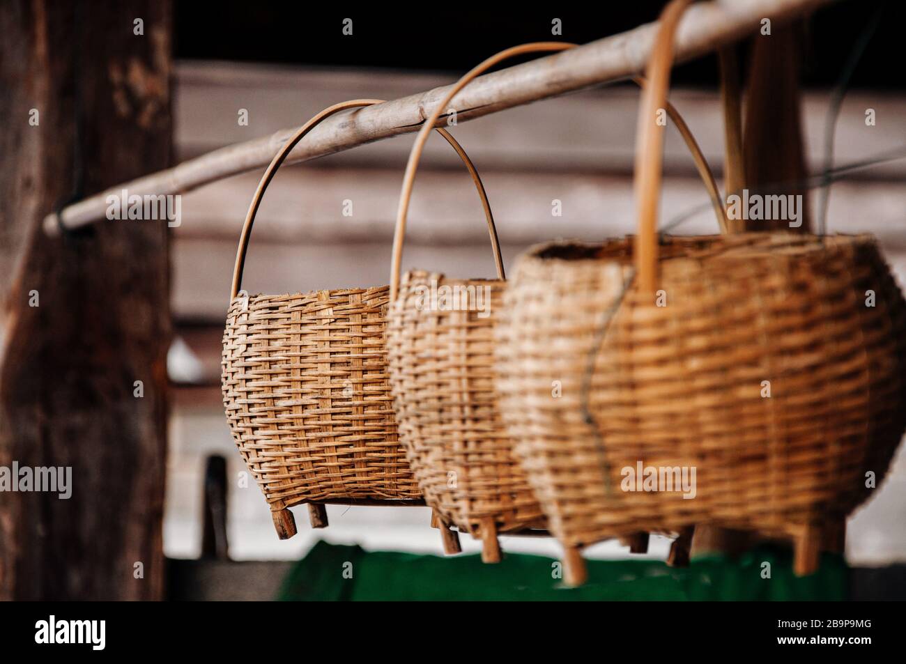 Wicker Bambus Rattan Korb im asiatischen Stil mit Holzgriff, der auf Bambusstäbchen im Bauernhaus hängt Stockfoto