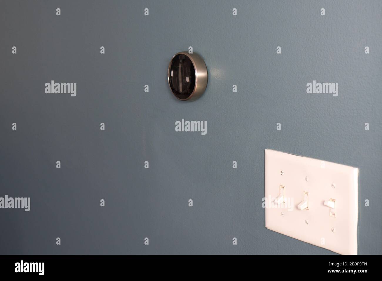 Smart Home Thermostat an der Wand mit Lichtschalter. Zwei Möglichkeiten, Geld zu sparen! Licht und Temperatur Stockfoto