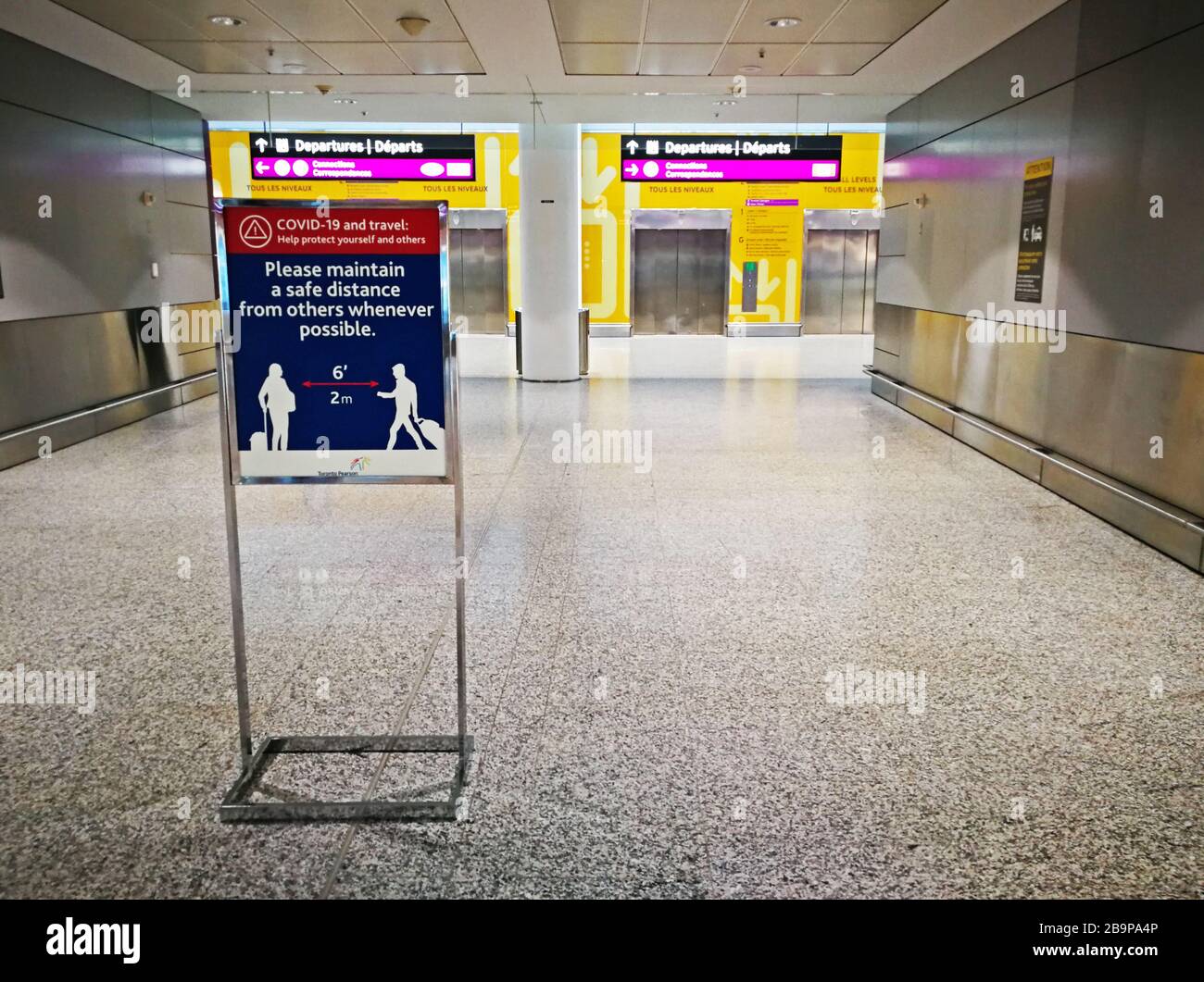 Schild, das die Flugreisenden daran erinnert, während der Covid-19 auch eine neuartige Coronavirus-Pandemie im fast leeren Toronto Pearson International Airport am 24. März 2020 in einem Sicherheitsabstand von 2 Metern voneinander zu halten. Stockfoto