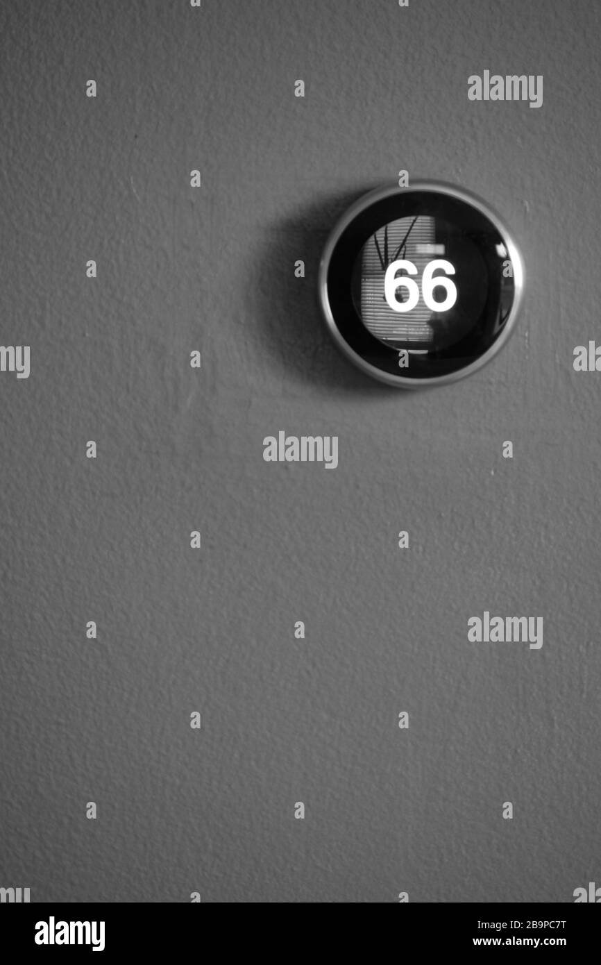 Smart Home Thermostat an blauer Wand isoliert. Temperatur wird auf dem Bildschirm angezeigt. Schwarz und Weiß Stockfoto