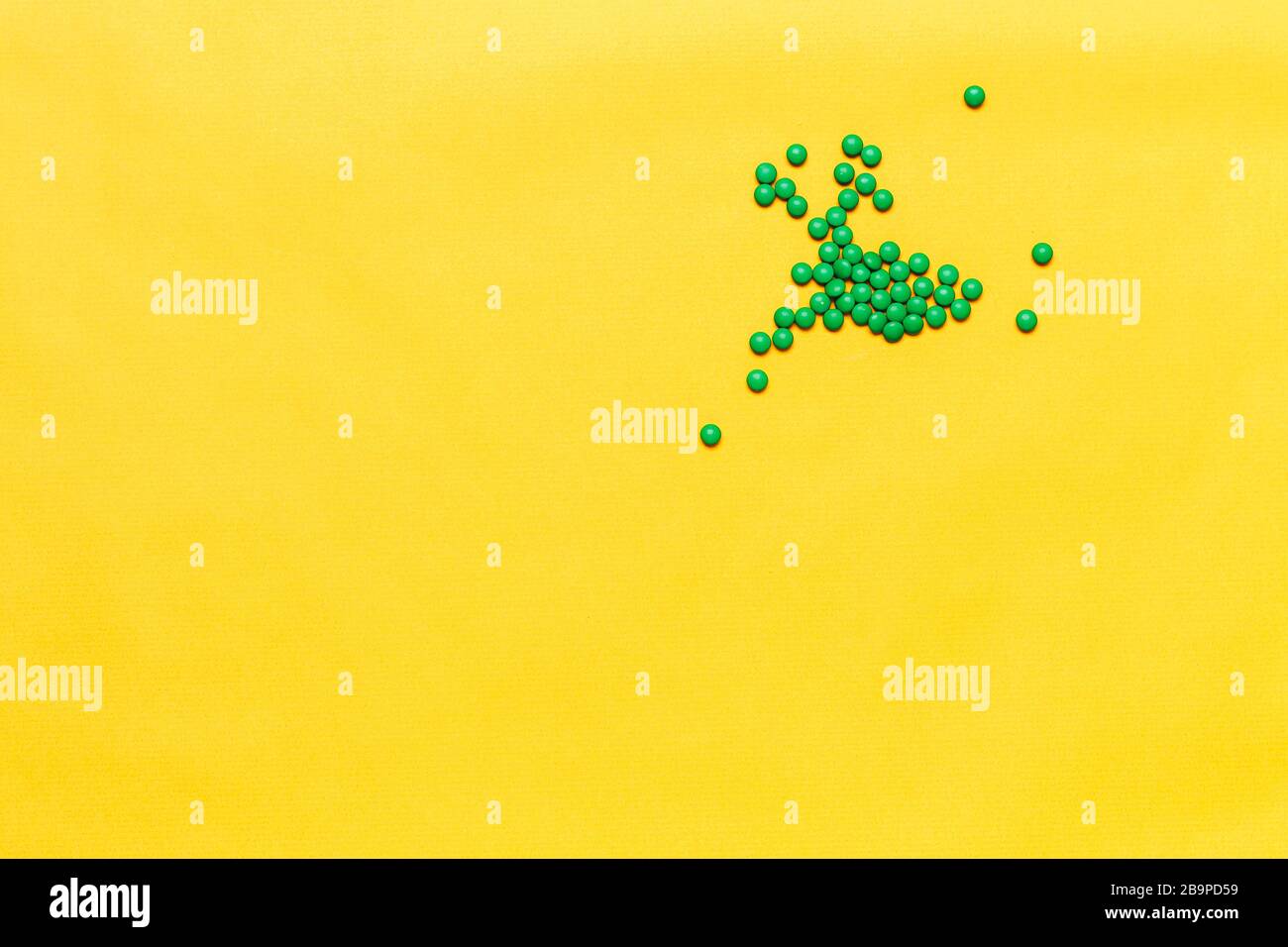 Kleine grüne, runde Tabletten auf gelbem Hintergrund. Copyspase, Platz für Text Stockfoto