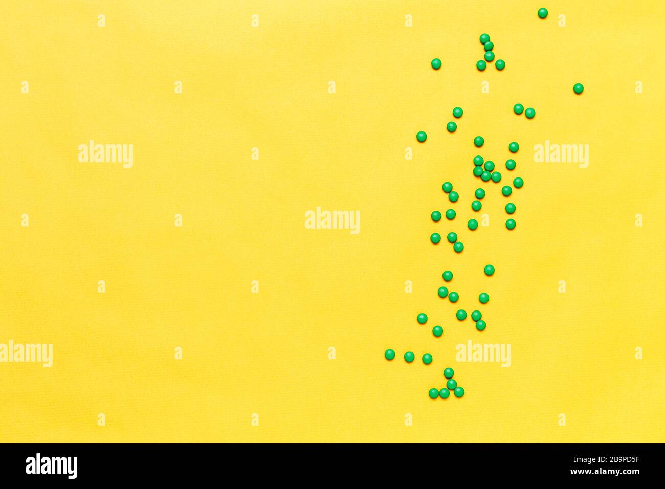 Kleine grüne, runde Tabletten auf gelbem Hintergrund. Copyspase, Platz für Text Stockfoto