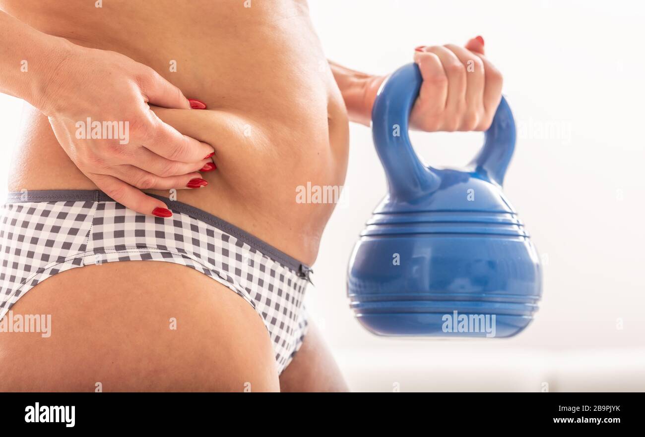 Übergewichtiger Fettkörper der Frau mit Hanteln in der Hand. Sportkonzept mit reduzem Bauch und gesundem Lebensstil Stockfoto