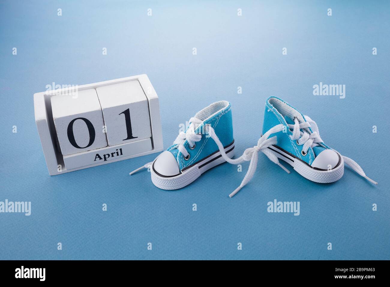 April Narrentag. Überraschungssymbol. Schnürsenkel auf blauem Holzhintergrund zusammengebunden. April Narr. Stockfoto